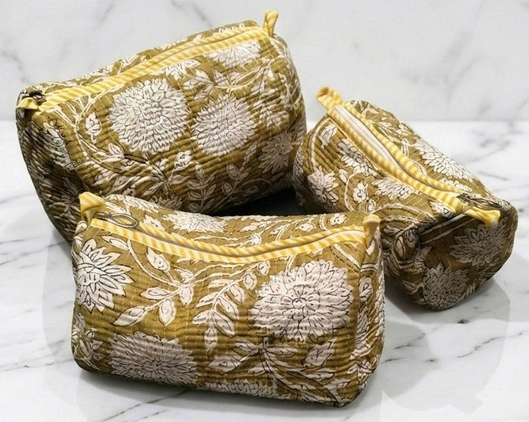 Three yellow and white floral-patterned pouches on a marble surface